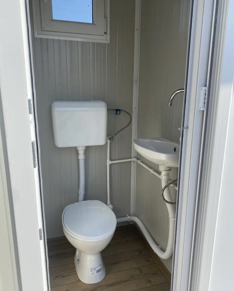 Deluxe flushing restroom unit with a tank toilet and small sink
