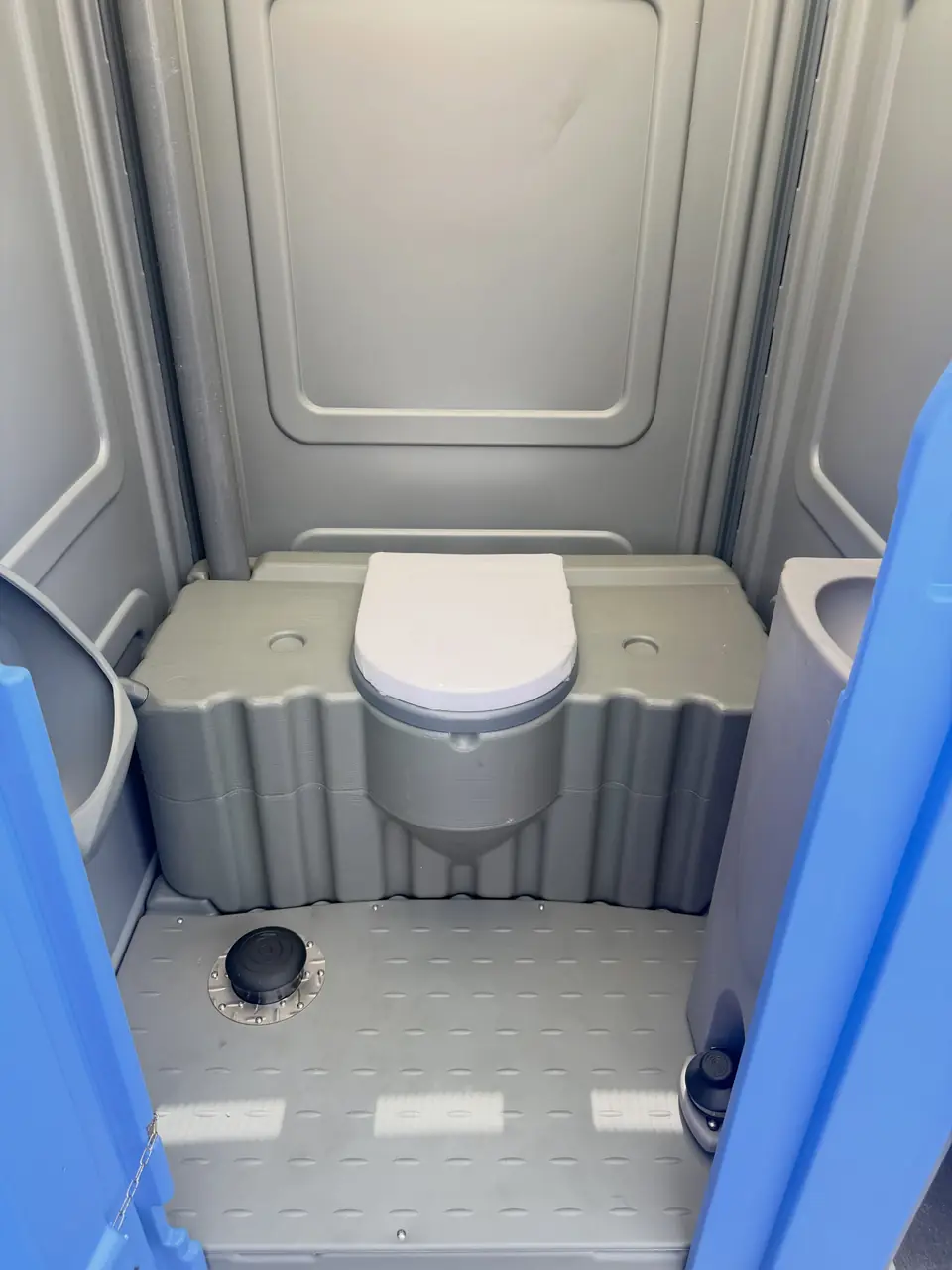 Clean seat inside a grey standard porta potty