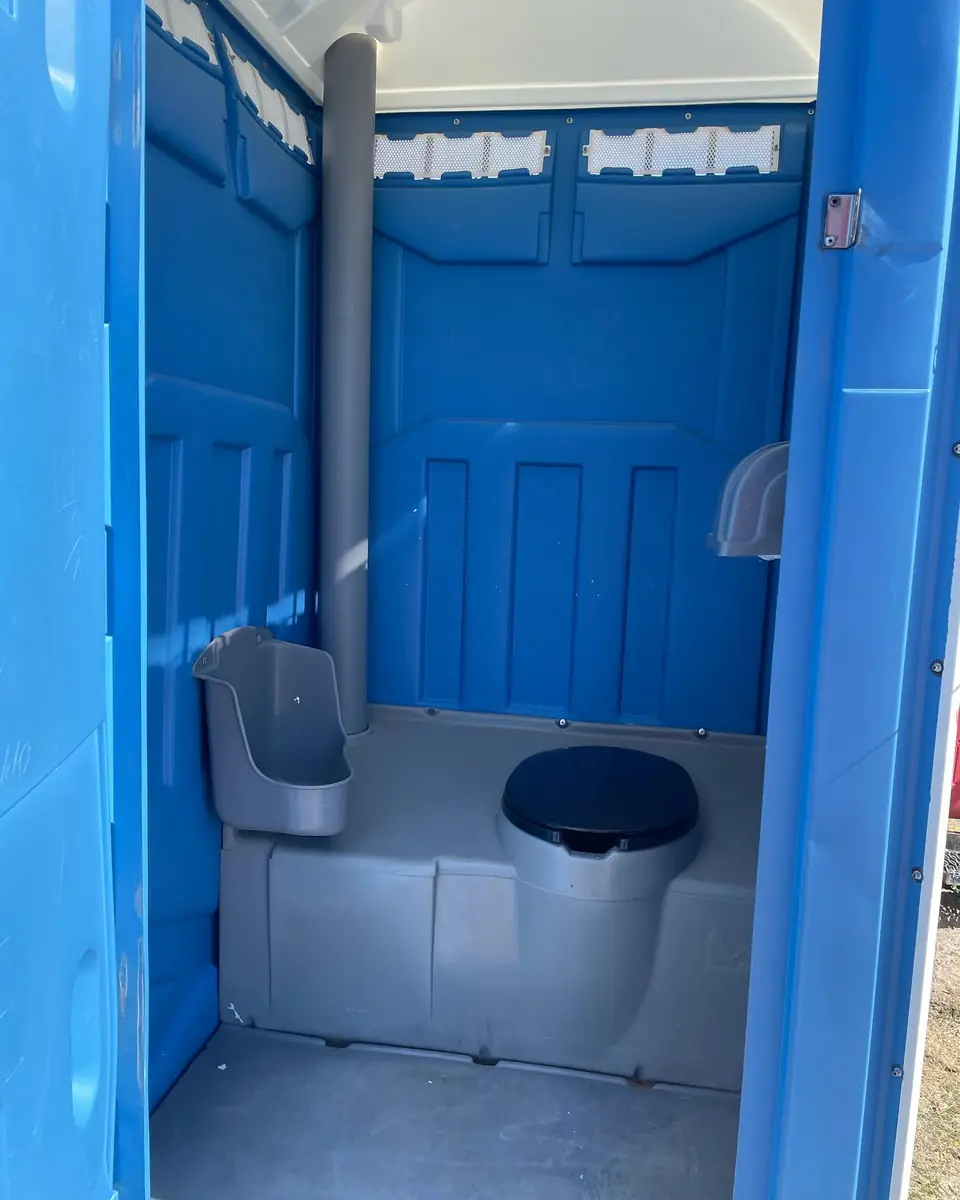 Inside a standard porta potty showing the seat and urinal
