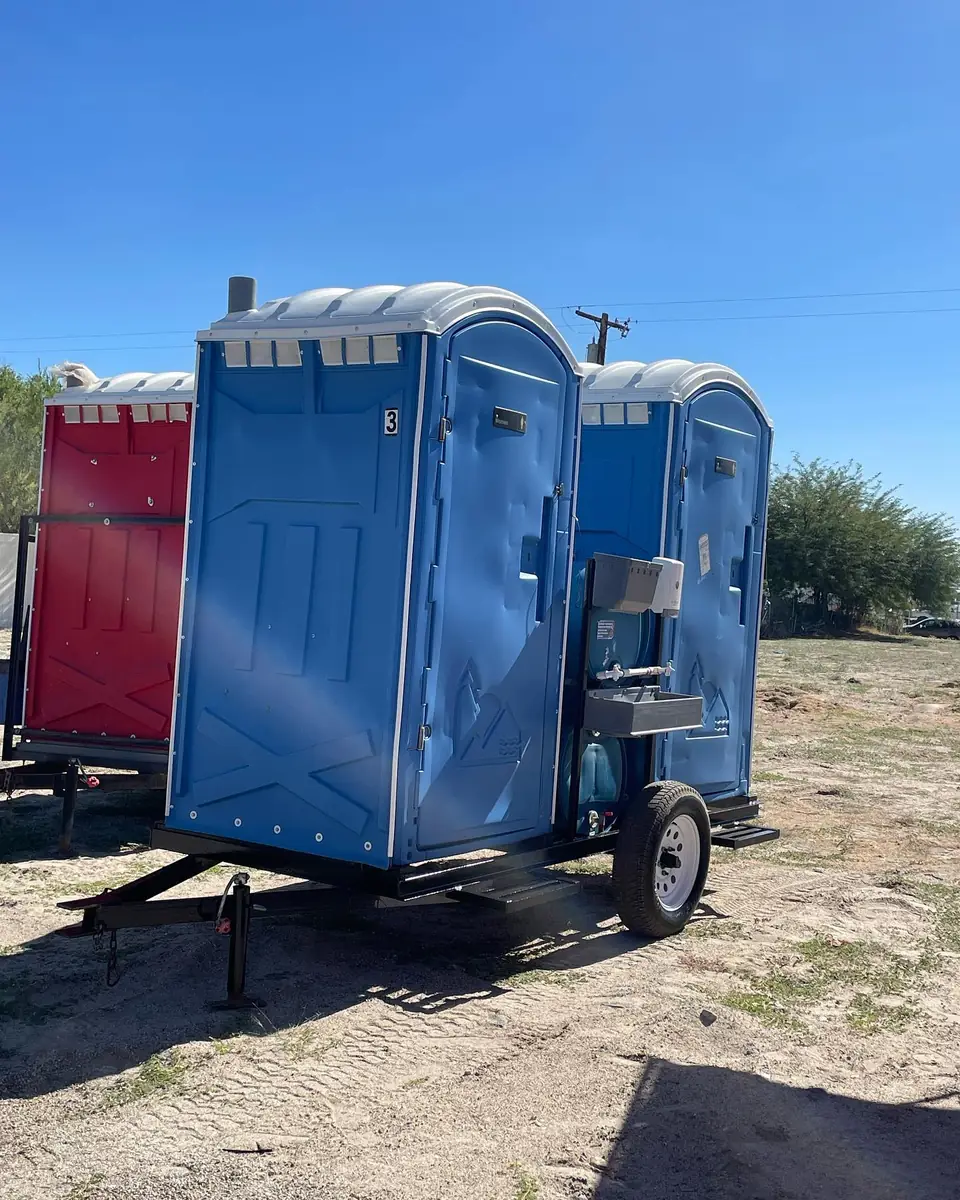 Blue porta potty mounted on a small tow trailer