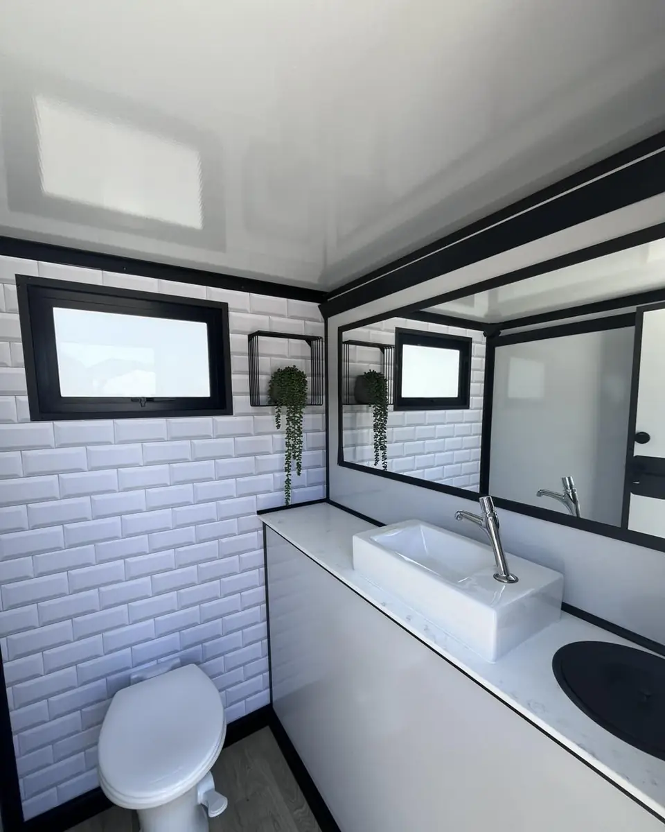 Restroom trailer interior with white tile, toilet and sink counter
